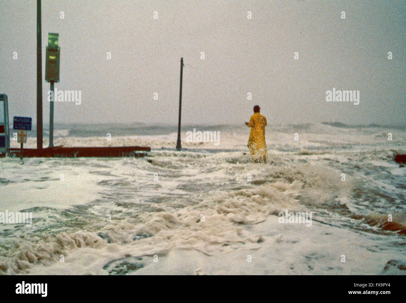 Ocean City, Maryland, USA, 28th September, 1985 Hurricane Gloria comes ashore in Ocean City, Maryland. The center eye of Gloria passed about 30 miles offshore eastern Maryland. In Ocean City, waves of 15 ft  severely damaged the boardwalk, washing sand and debris a block inland. High waves in Maryland eroded beaches, wrecked dunes, and damaged oceanfront buildings and boardwalks. Radio reporter Ross SImpson walks out onto the boardwalk to record the sound of the storm and do a live radio broadcast from the phone booth during height of the storm  Credit: Mark Reinstein Stock Photo