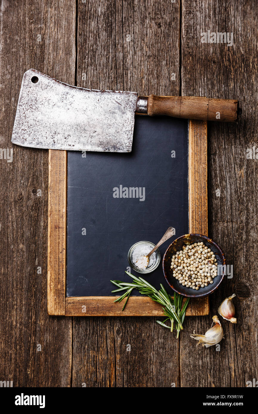 Vintage slate chalk board, Butcher meat cleaver and spices on wooden background Stock Photo