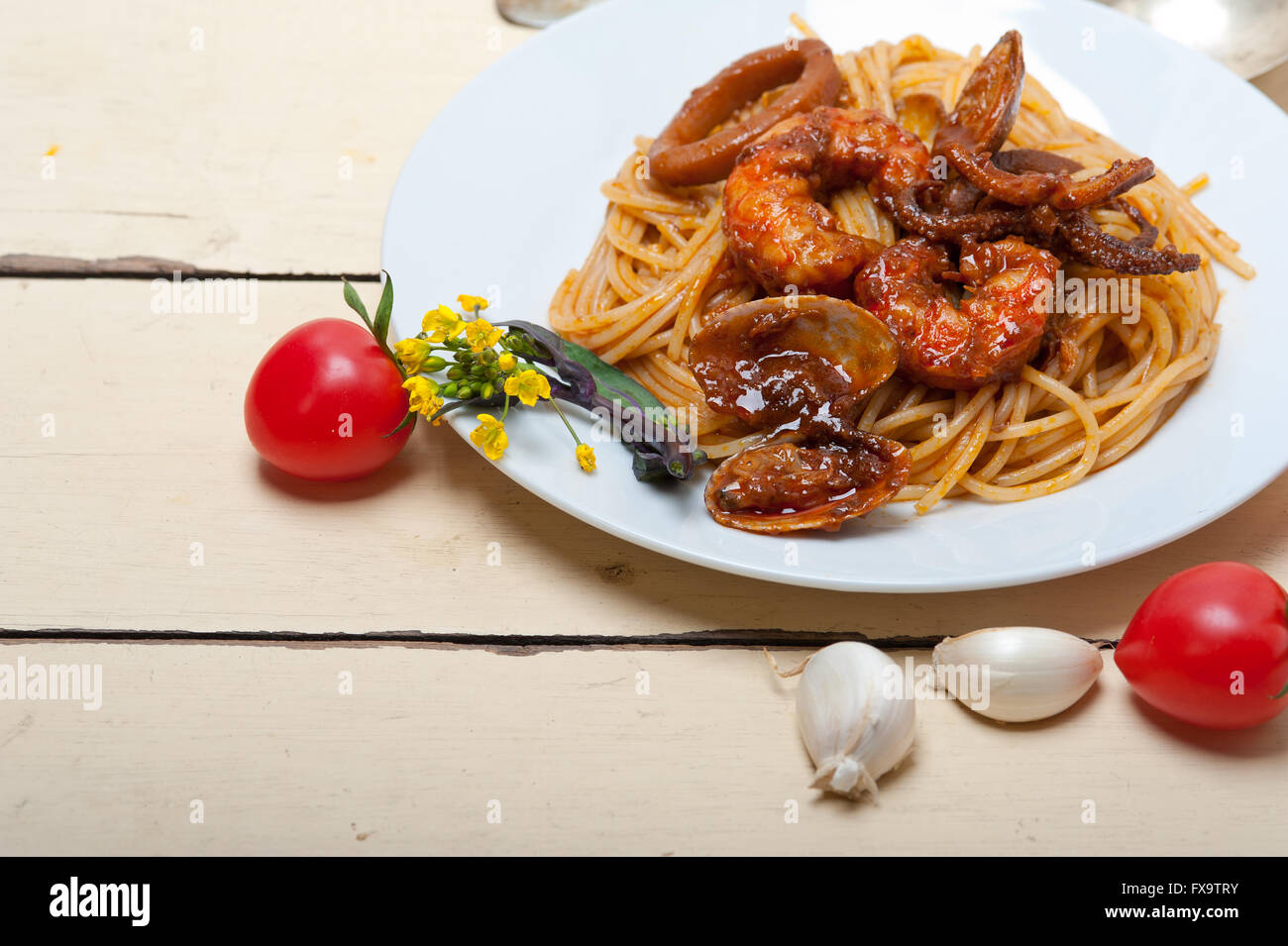 Italian seafood spaghetti pasta on red tomato sauce over white rustic
