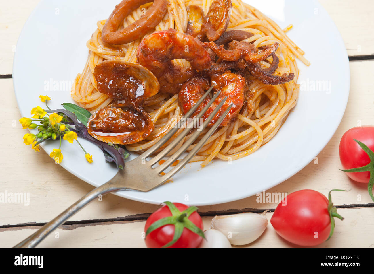 Italian seafood spaghetti pasta on red tomato sauce over white rustic