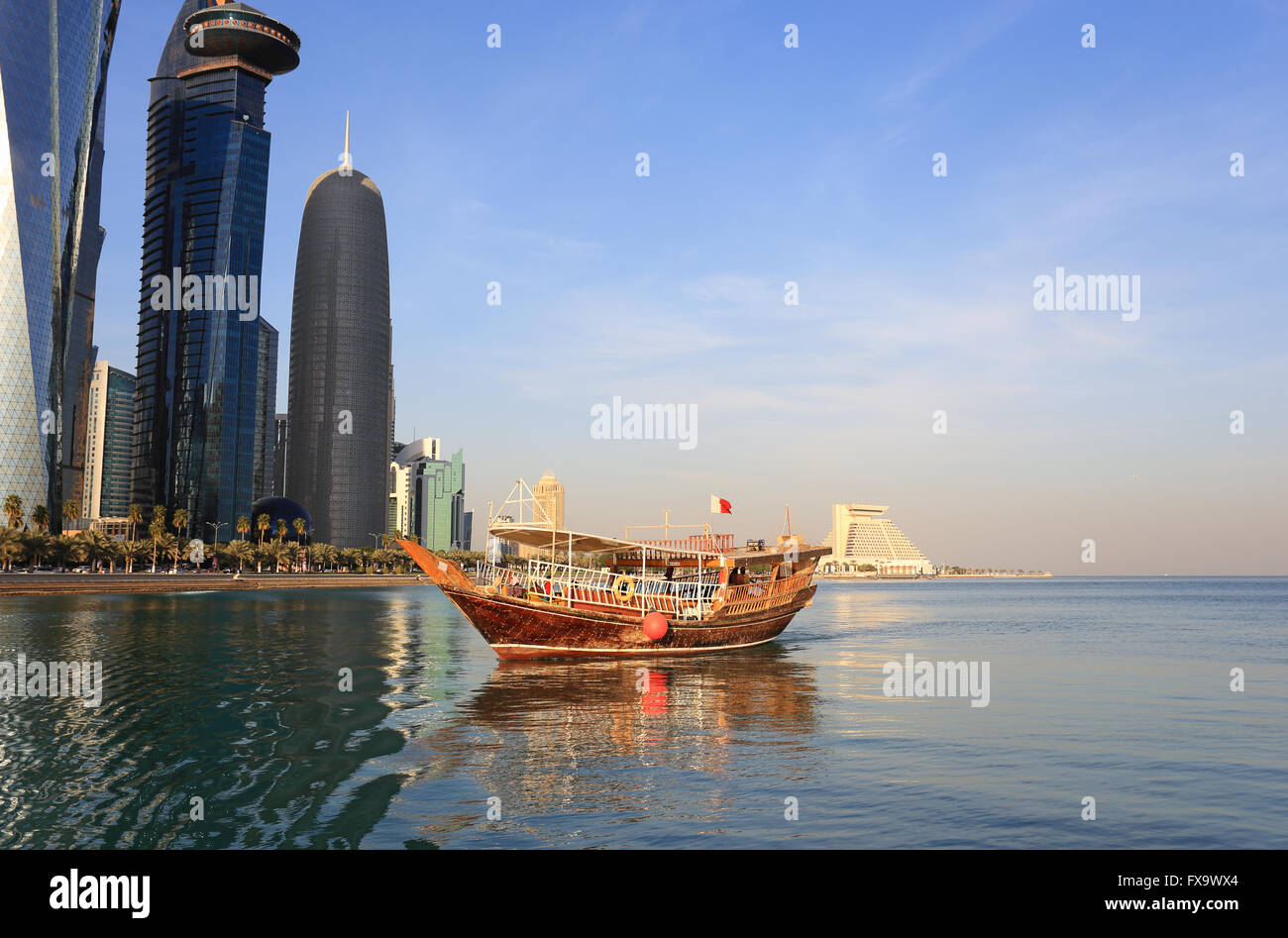 A pleasure dhow sailing in Doha Bay, Qatar, under the shadow of the city's huge towers, January 2016 Stock Photo