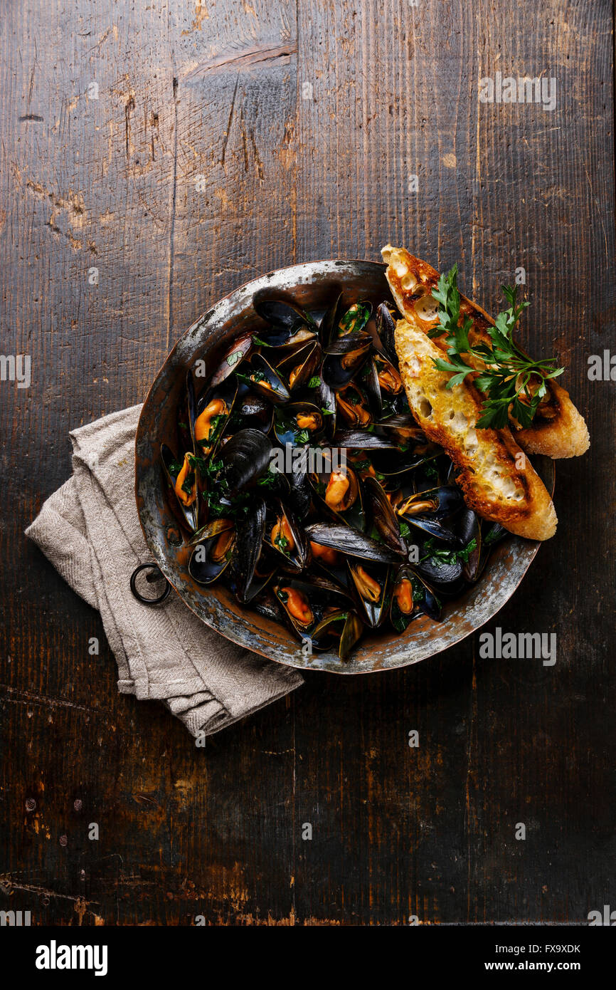 Mussels with parsley and bread toasts on dark background Stock Photo