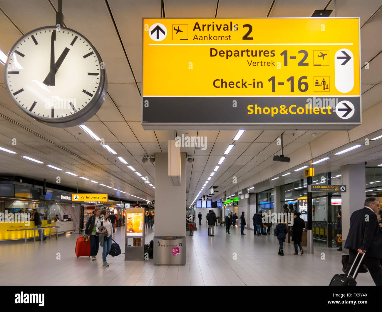 Signs, clock and travellers in terminal of Schiphol Amsterdam Airport, Netherlands Stock Photo