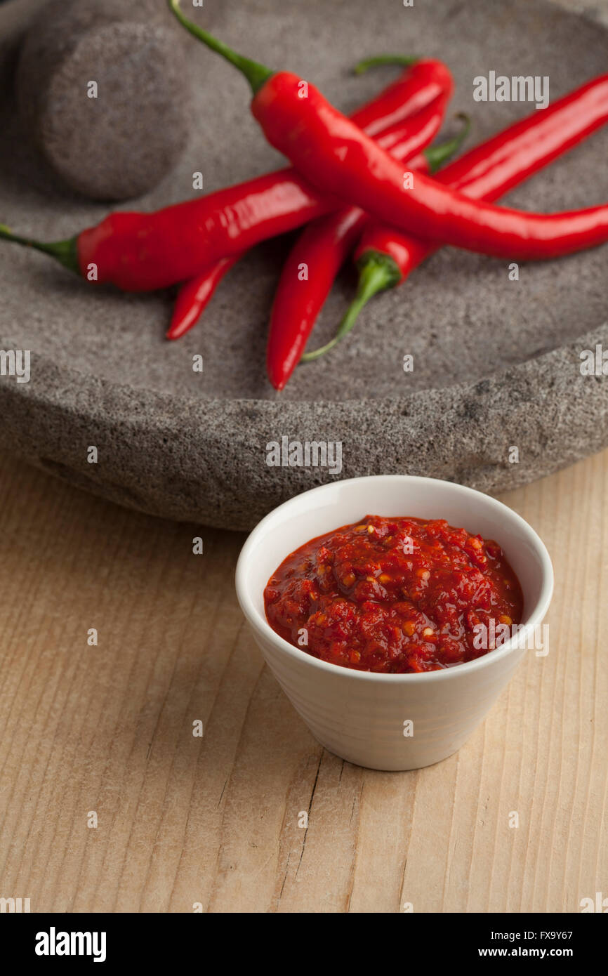 Bowl with traditional Indonesian Sambal and fresh red chili peppers Stock Photo