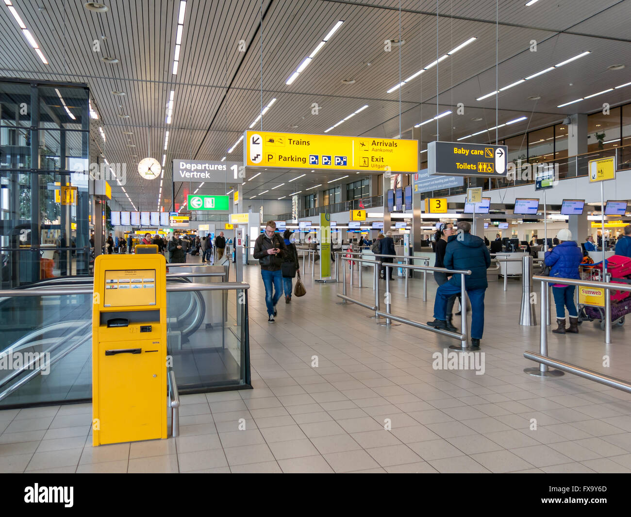 Signs, clock and travellers in departure terminal of Schiphol Amsterdam Airport, Netherlands Stock Photo