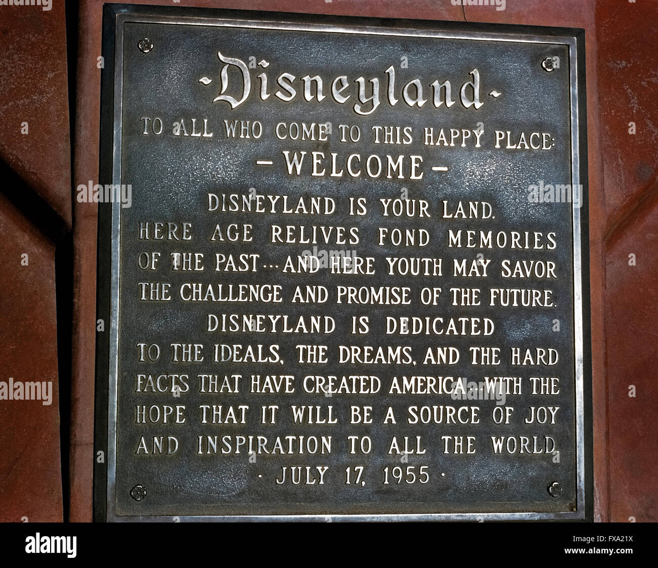 A dedication plaque commemorates the grand opening of the world’s most famous theme park, Disneyland, on July 17, 1955, in Anaheim, California, USA.  The metal tablet features a welcome “to this happy place” by Disneyland’s namesake creator, Walt Disney, who read the inscription to thousands of first-day guests and a nationwide audience during a ceremony on live television.  Today’s park visitors will find the plaque at the base of the pole flying the American flag at the south end of Main Street, U.S.A. Stock Photo