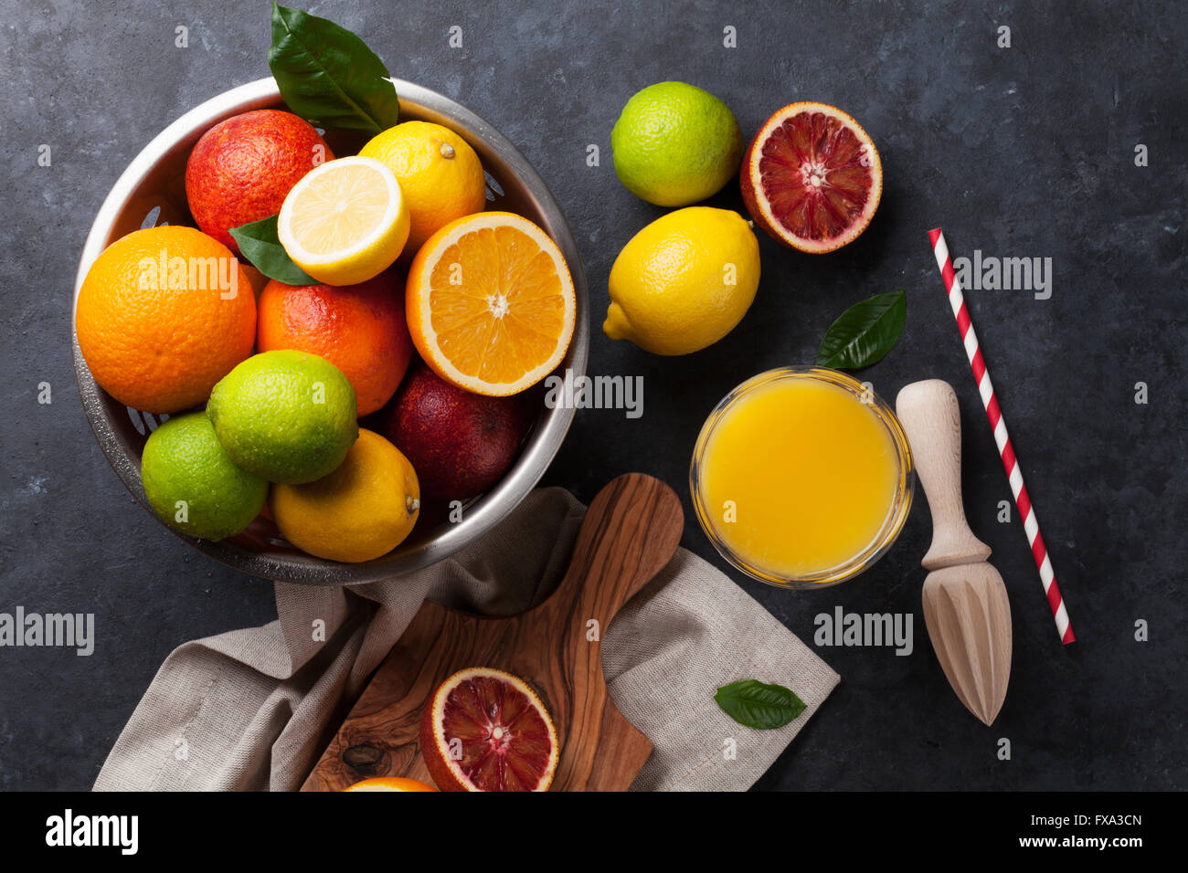 Fresh ripe citruses and juice. Lemons, limes and oranges on dark stone background. Top view Stock Photo