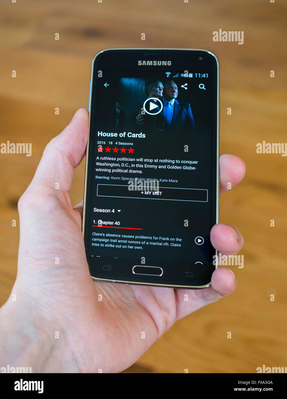 A hand holding a Samsung phone with the Netlfix app open, showing the tv show House of Cards. Stock Photo