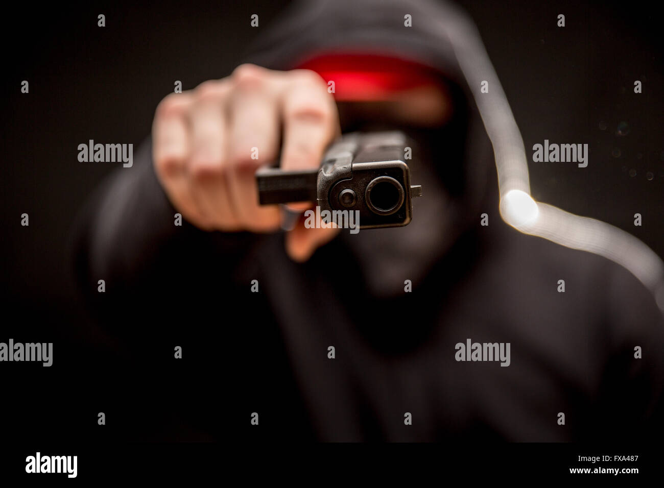 A young criminal points a sideways handgun at the viewer. Stock Photo