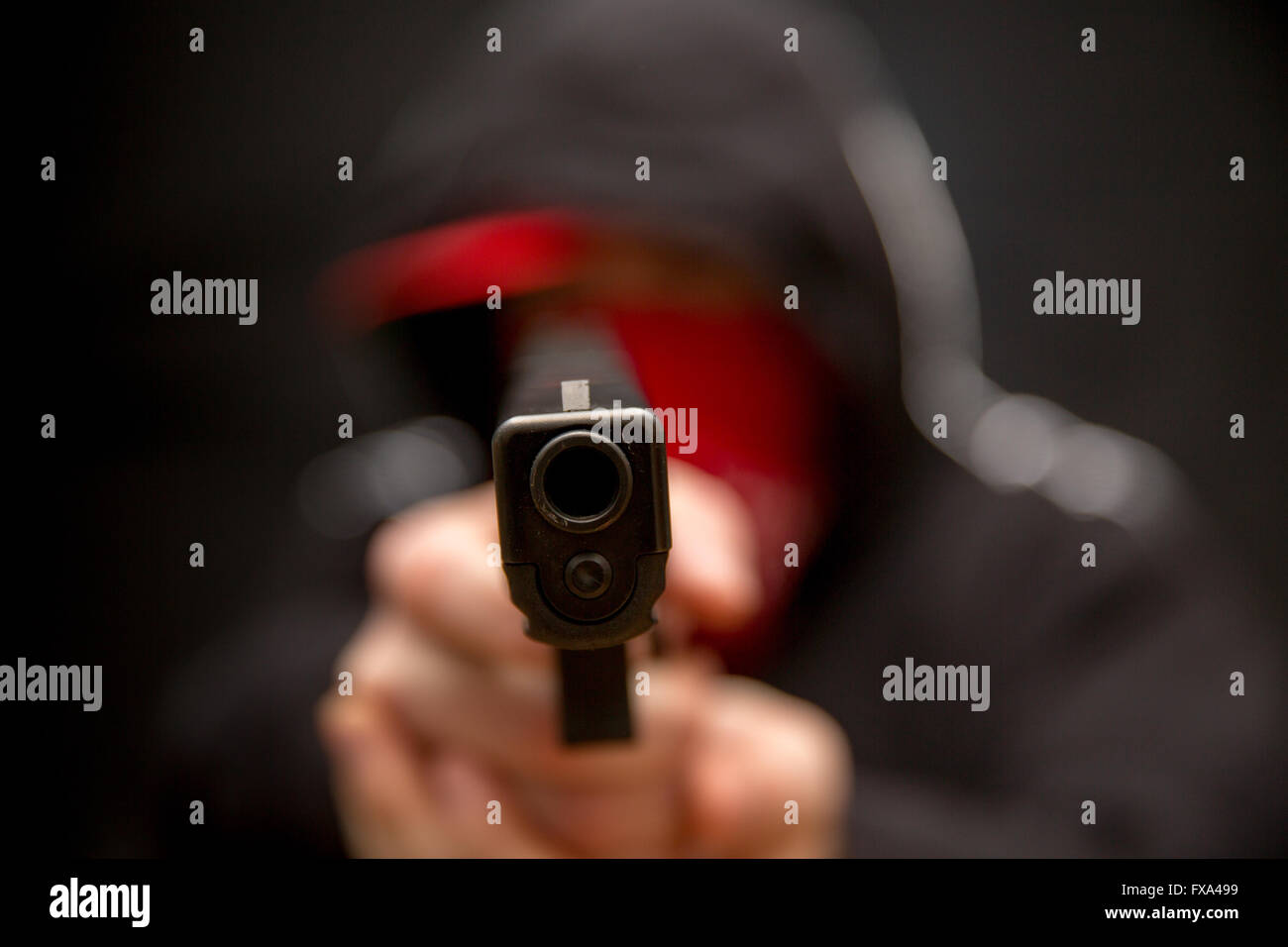 A young criminal points a semi-auto handgun at the viewer Stock Photo