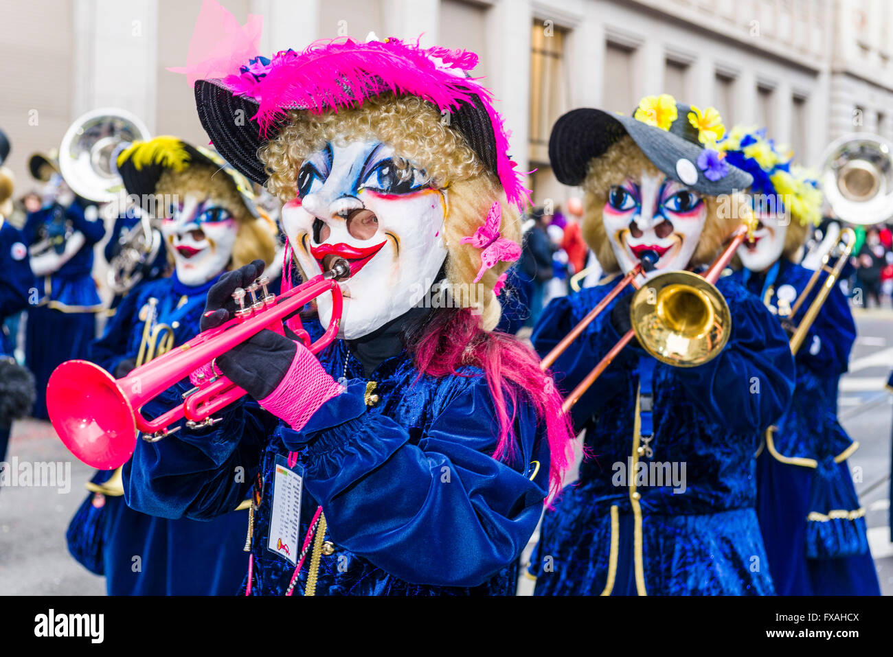 Members of the Gugge marching brass bands wearing fancy dresses and masks at the great procession of the Carnival of Basel Stock Photo
