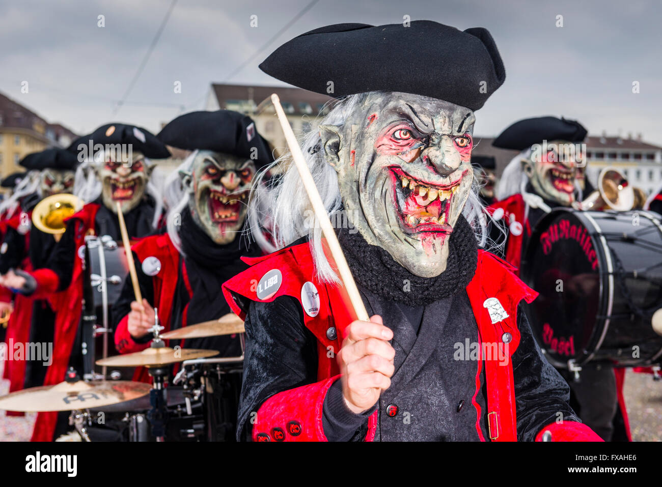 Members of the Gugge marching brass bands wearing fancy dresses and masks at the great procession at the Carnival of Basel Stock Photo