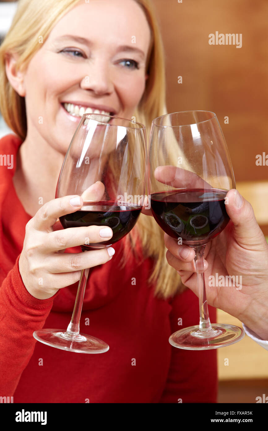 Elderly happy woman raises her glass of red wine for a toast Stock Photo