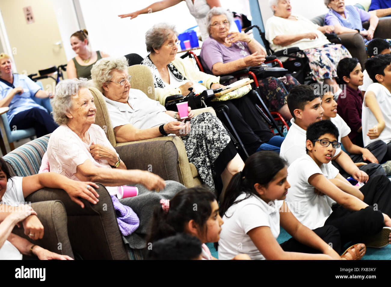 School children visit an elderly people's care home to develop intergenerational relationships. Stock Photo