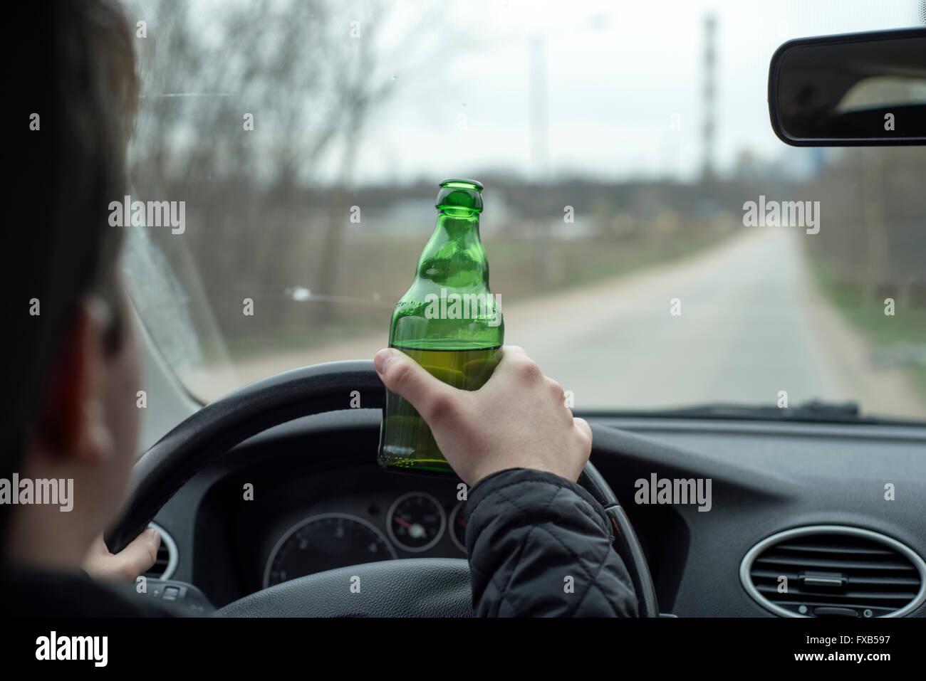 a picture of a young man drinking alcohol while driving Stock Photo