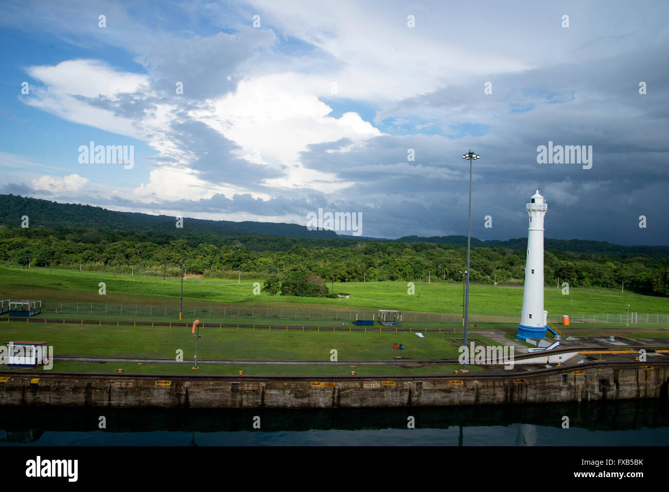 Tall white lighthouse for Northbound Atlantic stands in beautiful green environment overlooking Panama Canal near Gatun locks. Stock Photo