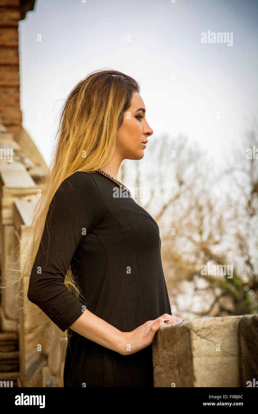 Portrait of attractive blonde young woman in black dress, outdoor looking to a side, profile portrait Stock Photo