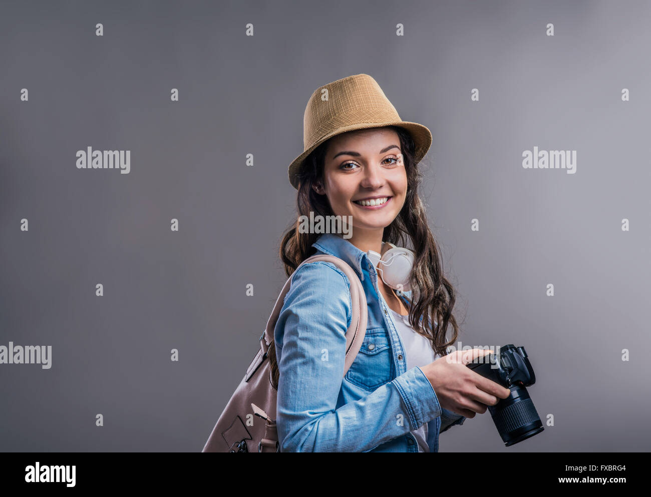 Tourist girl in denim shirt with camera, studio shot Stock Photo