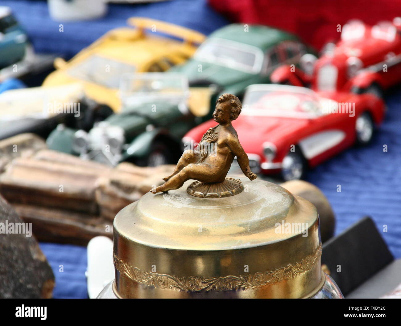 Small brass vintage figure of a child in the foreground with antique toy cars, flea market, Germany. Stock Photo