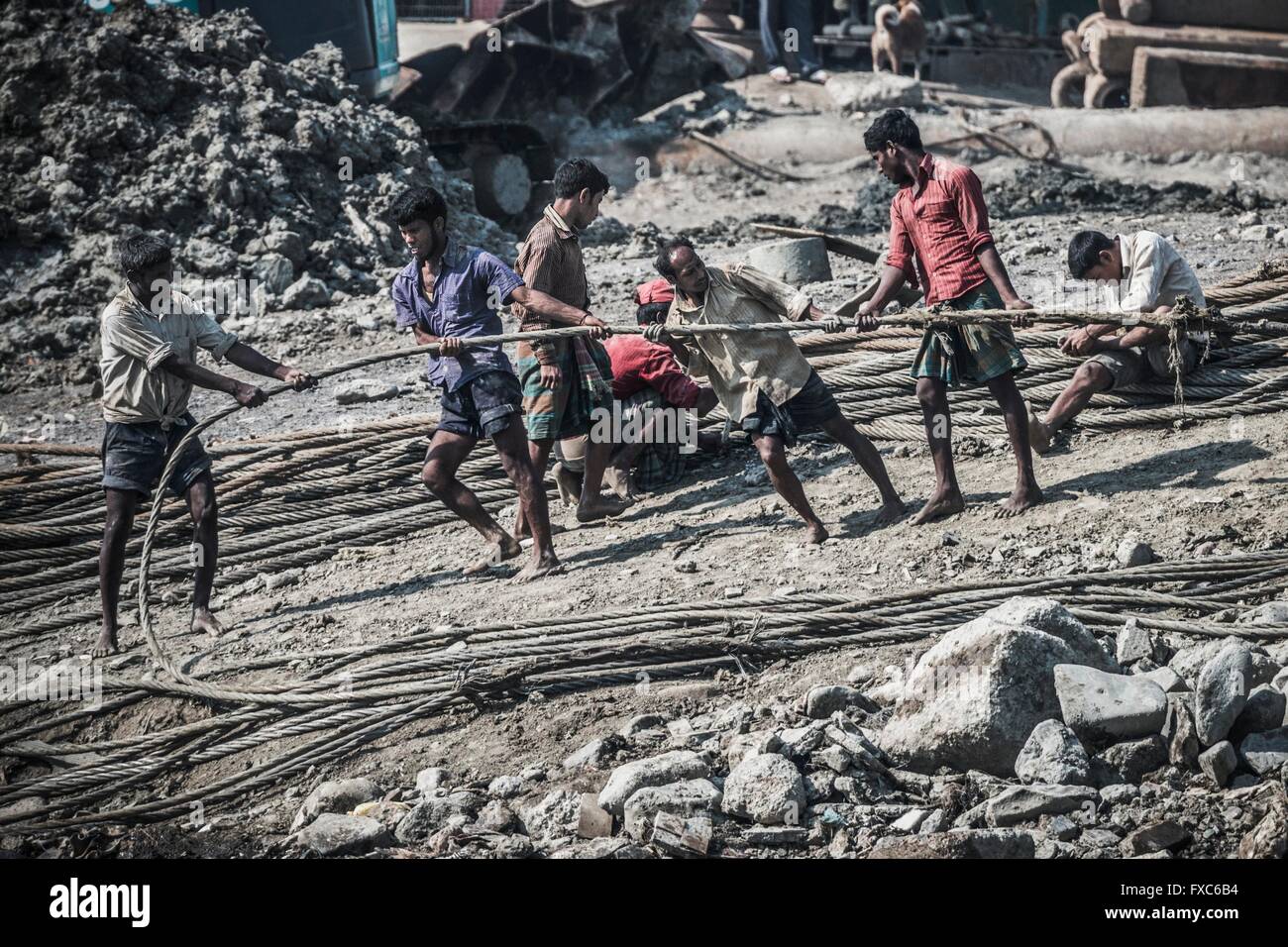 Workers are dragging a heavy pull rope in a shipbreaking yard in Chittagong. Once the beach at the shipwrecking places in Chittagong, Bangladesh were white and clean. Today Chittagong is partially soaked with oil and toxic mud. Stock Photo