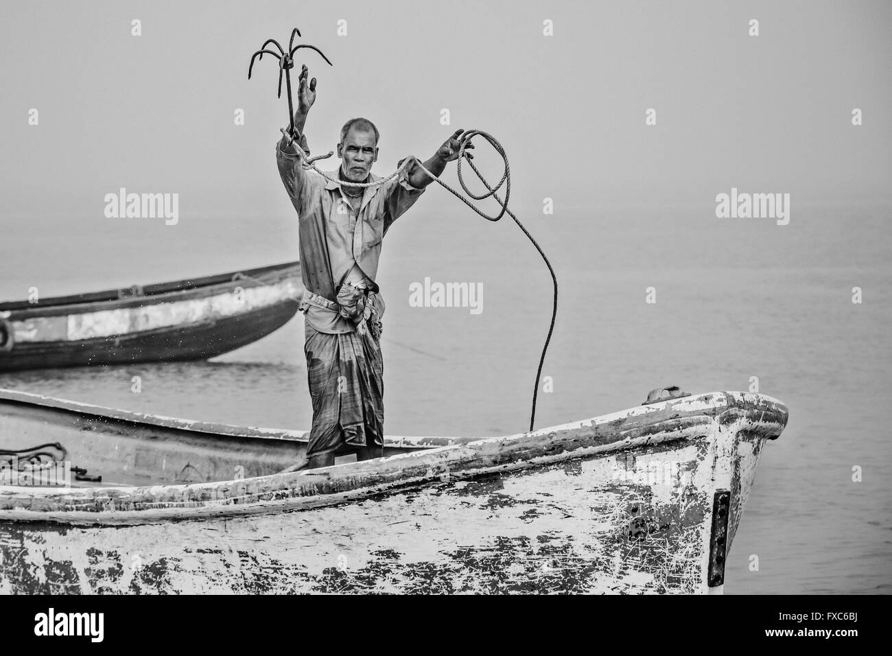 A fisherman throws in the vicinity of the shipbreaking yards of Chittagong in Bangladesh its anchor. Every morning fishermen in Chittagong go with their boats to contaminated fishing spots in the middle of one of the largest shipbreaking places the world. Stock Photo