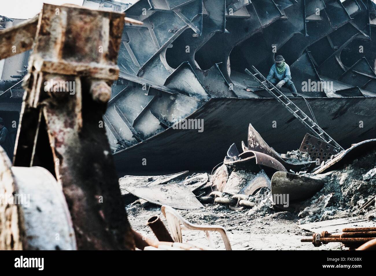 A worker cuts with a flame cutter ship parts apart. Once the beach at the shipwrecking places in Chittagong, Bangladesh were white and clean. Today Chittagong is partially soaked with oil and toxic mud. Stock Photo