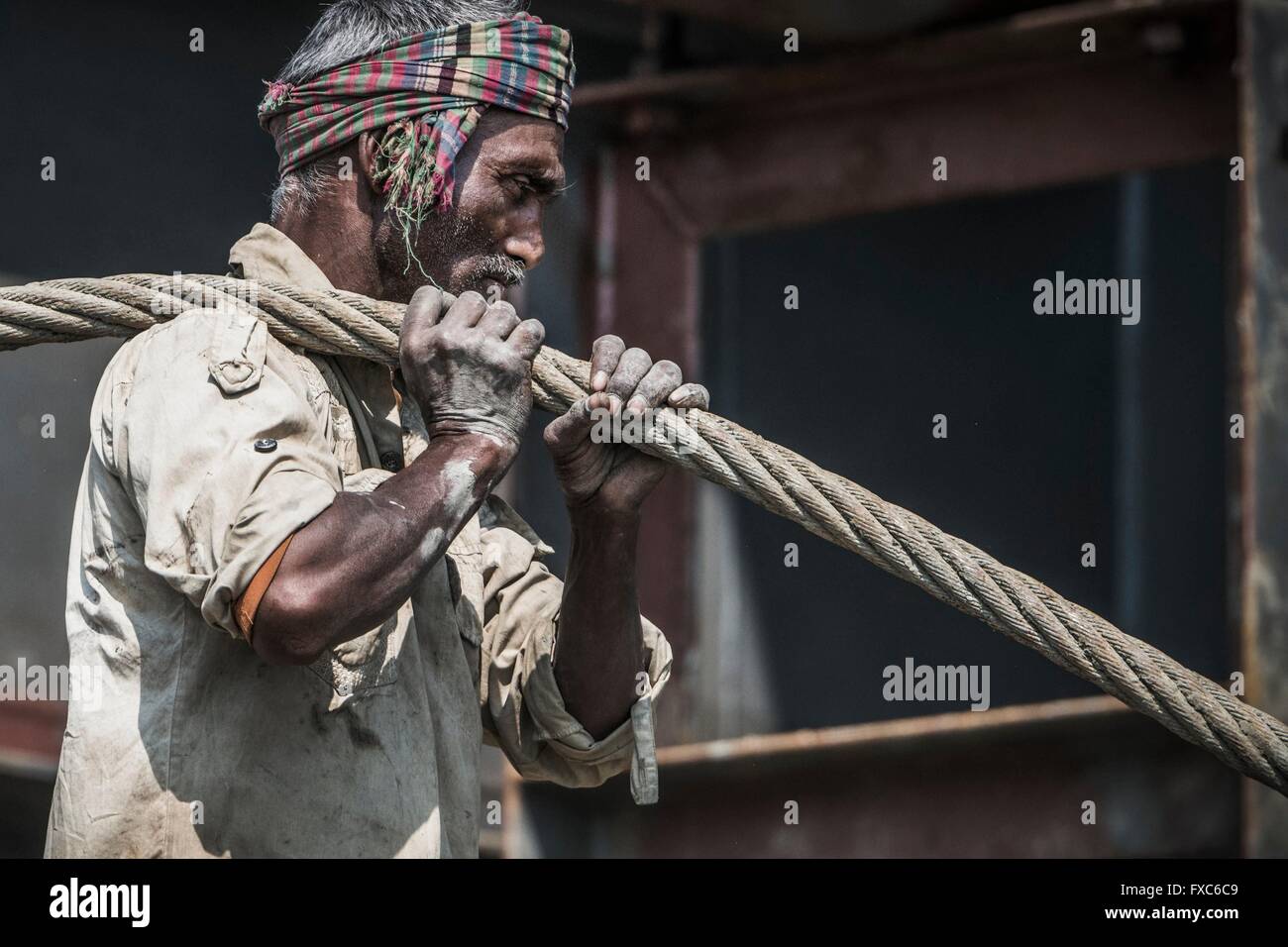 A worker is dragging a heavy pull rope in a shipbreaking yard in Chittagong. Once the beach at the shipwrecking places in Chittagong, Bangladesh were white and clean. Today Chittagong is partially soaked with oil and toxic mud. Stock Photo