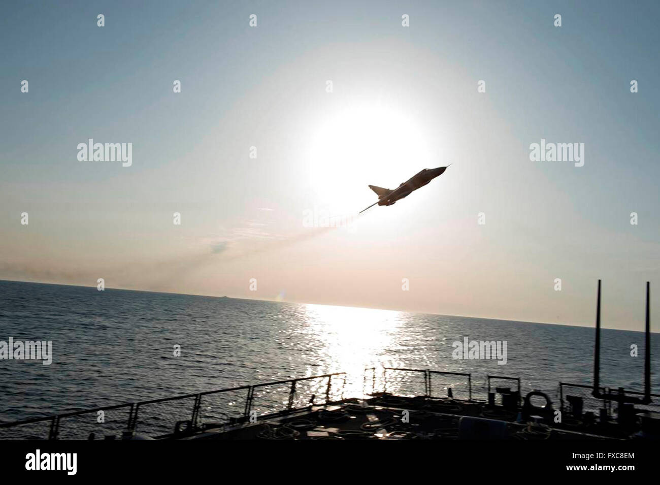 A Russian Sukhoi Su-24 attack aircraft makes a very low altitude pass over the bow of the U.S Navy Arleigh Burke-class guided-missile destroyer USS Donald Cook during a patrol April 12, 2016 in the Baltic Sea. The aggressive flight maneuvers by the Russian aircraft simulated a strafing run. Stock Photo
