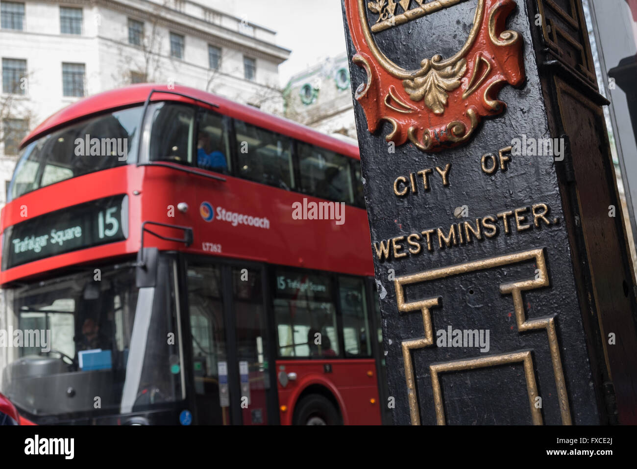 Historic post with coat of arms and passing red bus in City of Westminster London UK Stock Photo