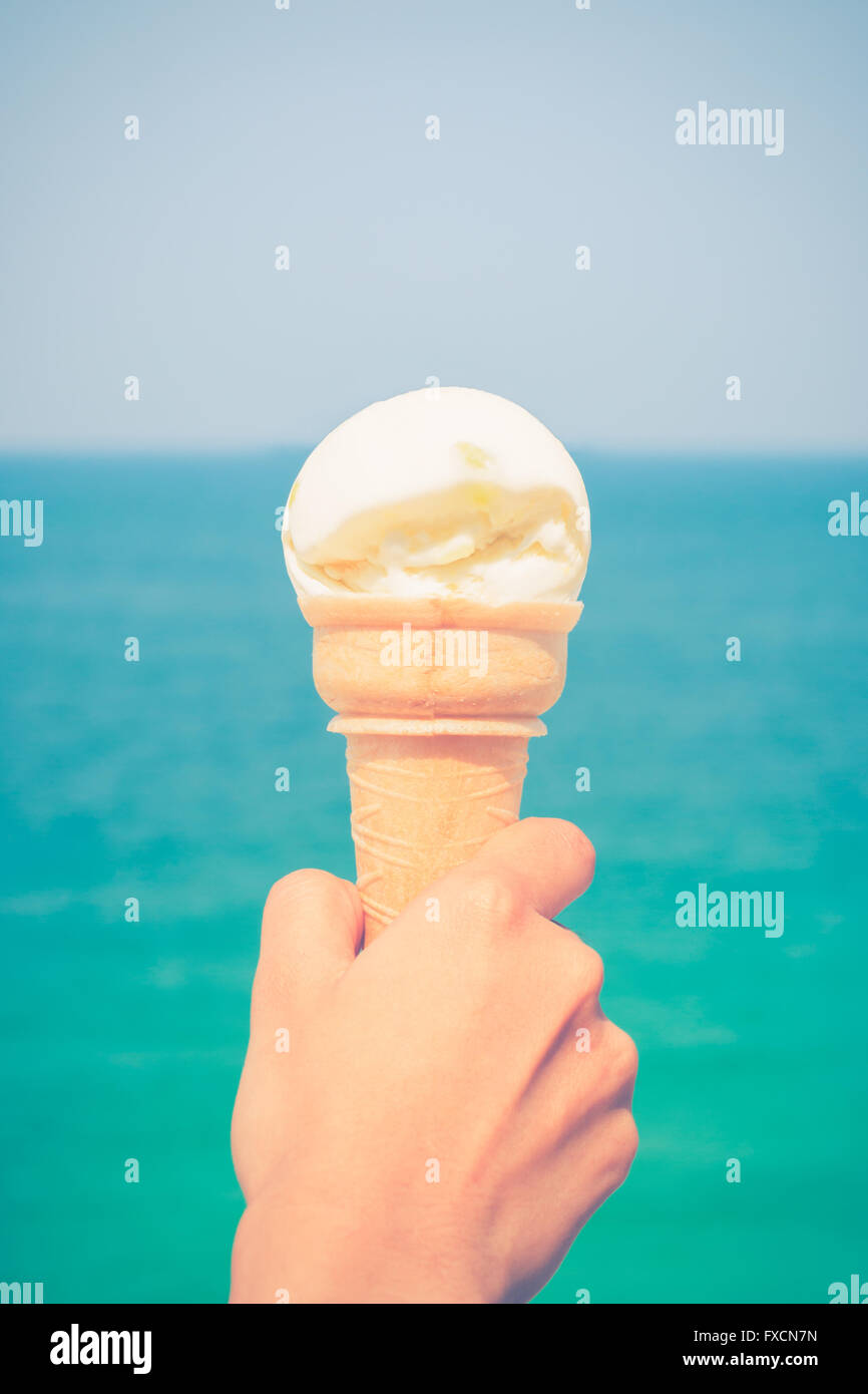 ice cream cone held up to the summer sky background the turquoise sea Stock Photo