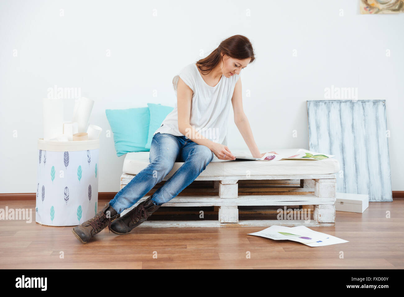 Thoughtful attractive woman painter sitting and using tablet in workshop Stock Photo