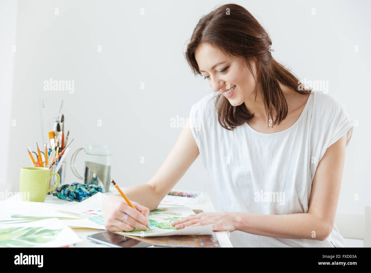 Smiling pretty woman painter drawing at the table Stock Photo