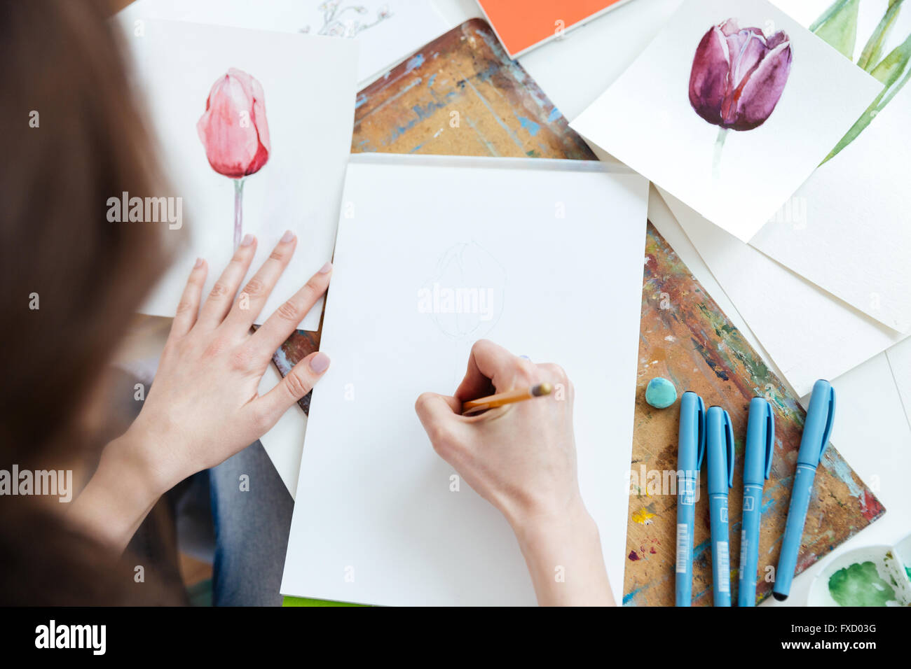 Top view of woman painter sitting and drawing by pencil at the table Stock Photo