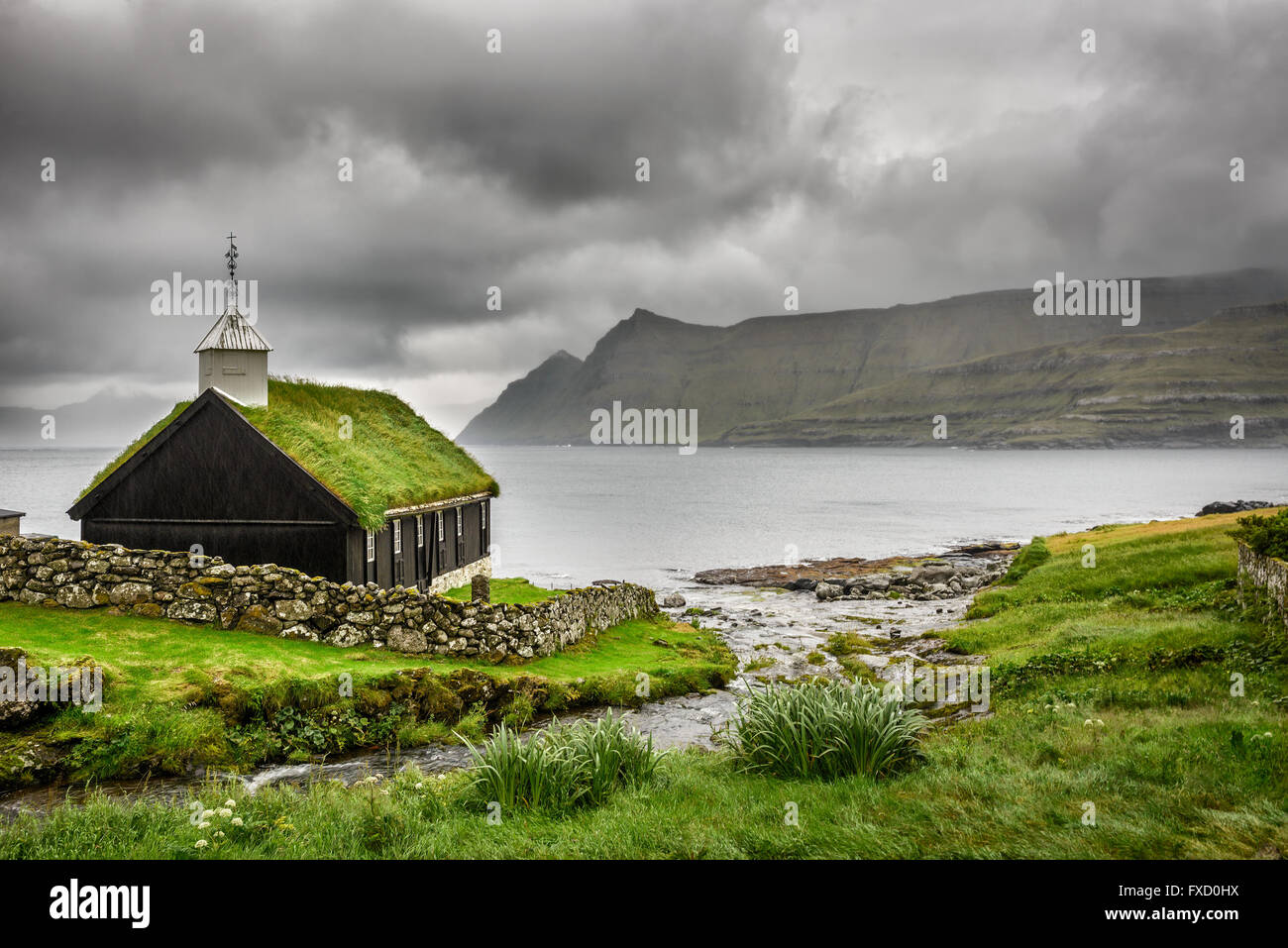 Small village church in Funningur under heavy clouds. Funningur is located on the island of Eysturoy, Faroe Islands, Denmark Stock Photo