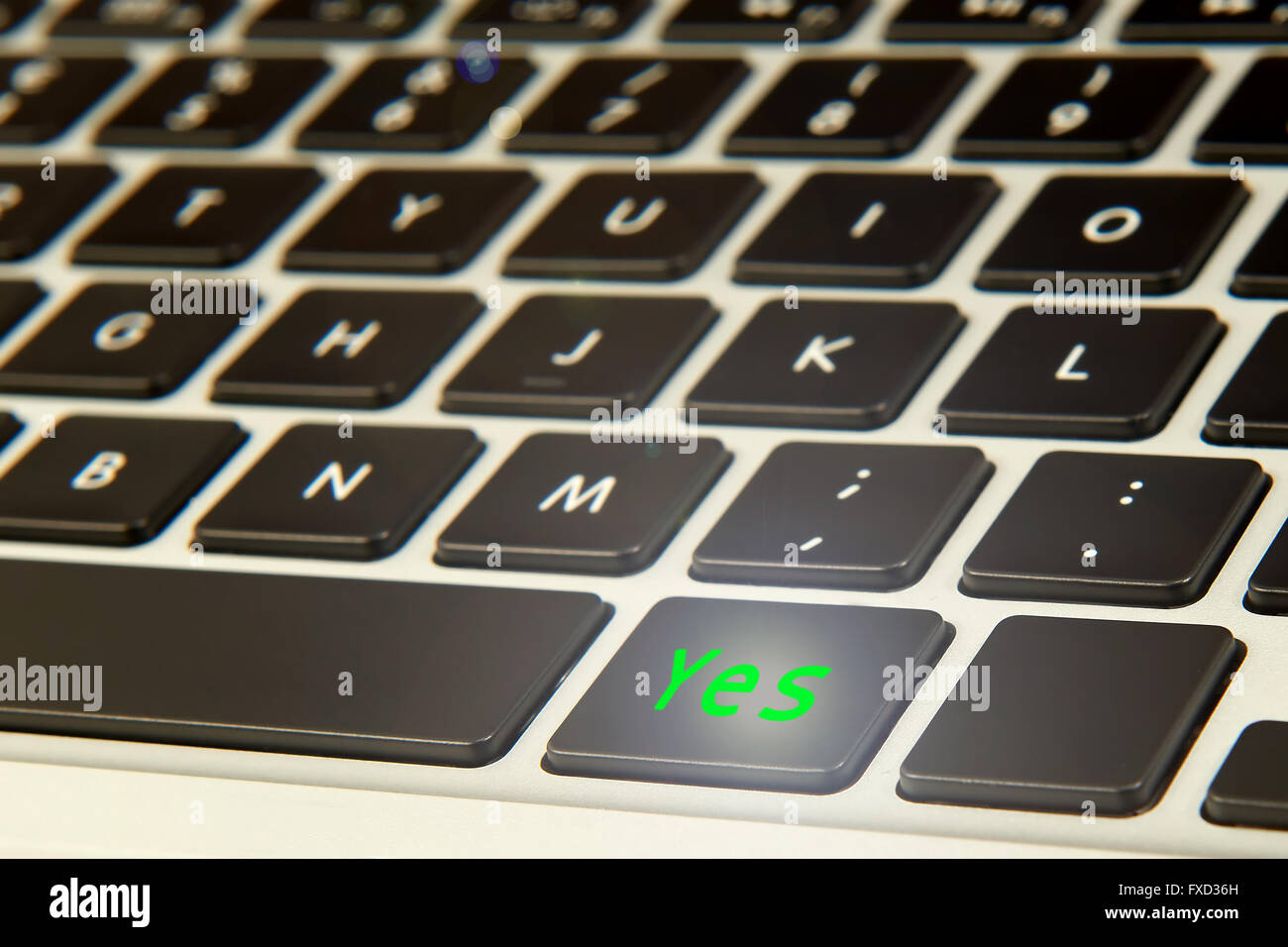 Computer keyboard with a green glowing yes button Stock Photo