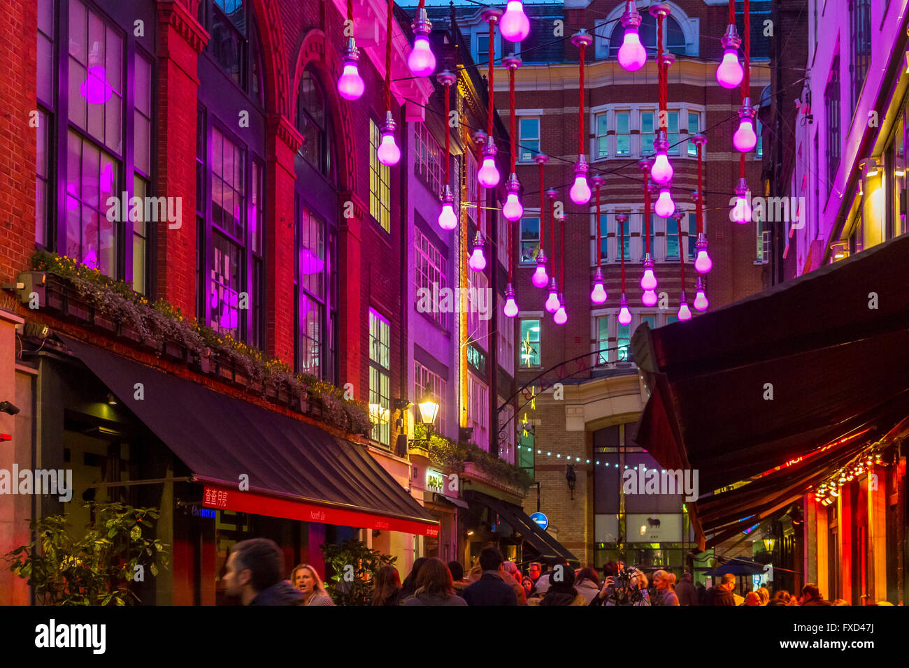 Giant illuminated purple light bulbs hanging from wires above  Ganton St in Soho, London, UK Stock Photo