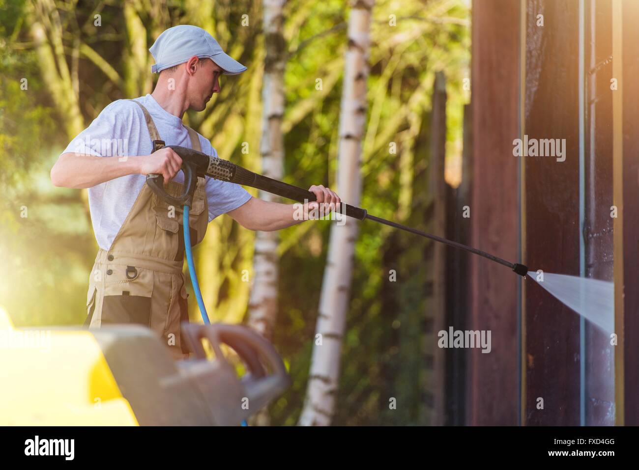 Spring Time House Walls Cleaning by High Pressure Water Spraying. Caucasian Men at Work. Stock Photo
