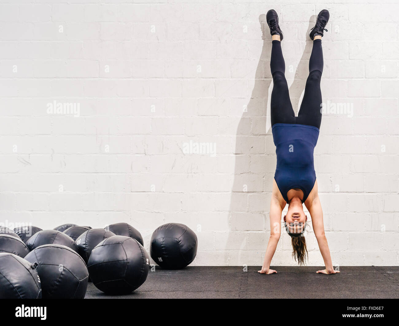Photo of a young fit woman doing a handstand exercise at a crossfit gym. Stock Photo