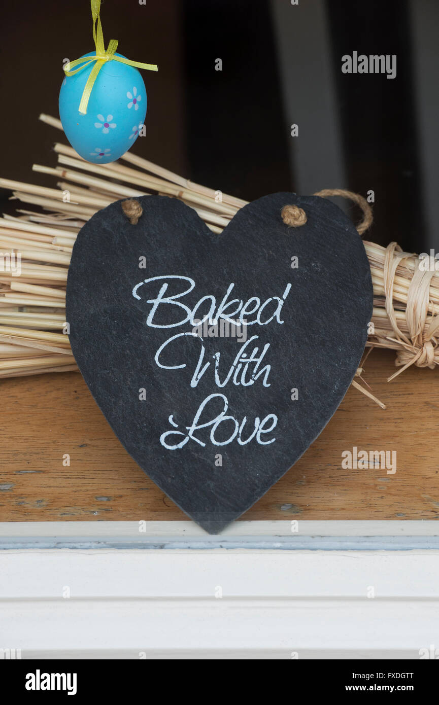 Baked with Love on a heart shape piece of slate in a shop window. Glastonbury, Somerset, England Stock Photo