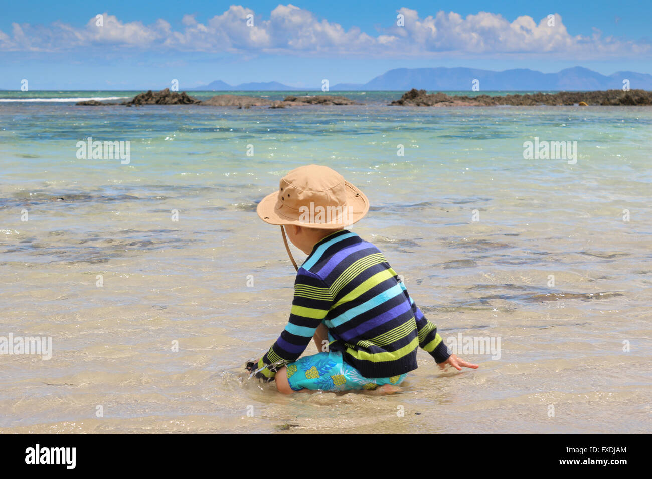 Photo of little boy splashing in shallow sea water with cloudy ...