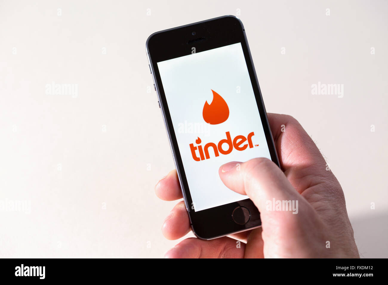 A man using the Tinder dating app on a mobile phone Stock Photo