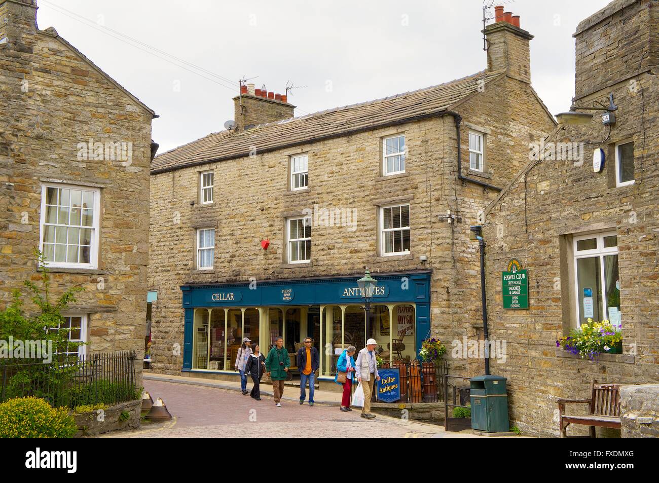 Japanese tourists walking past antiques shop in the Main Street. Hawes, Wensleydale, Yorkshire Dales National Park, Yorkshire. Stock Photo