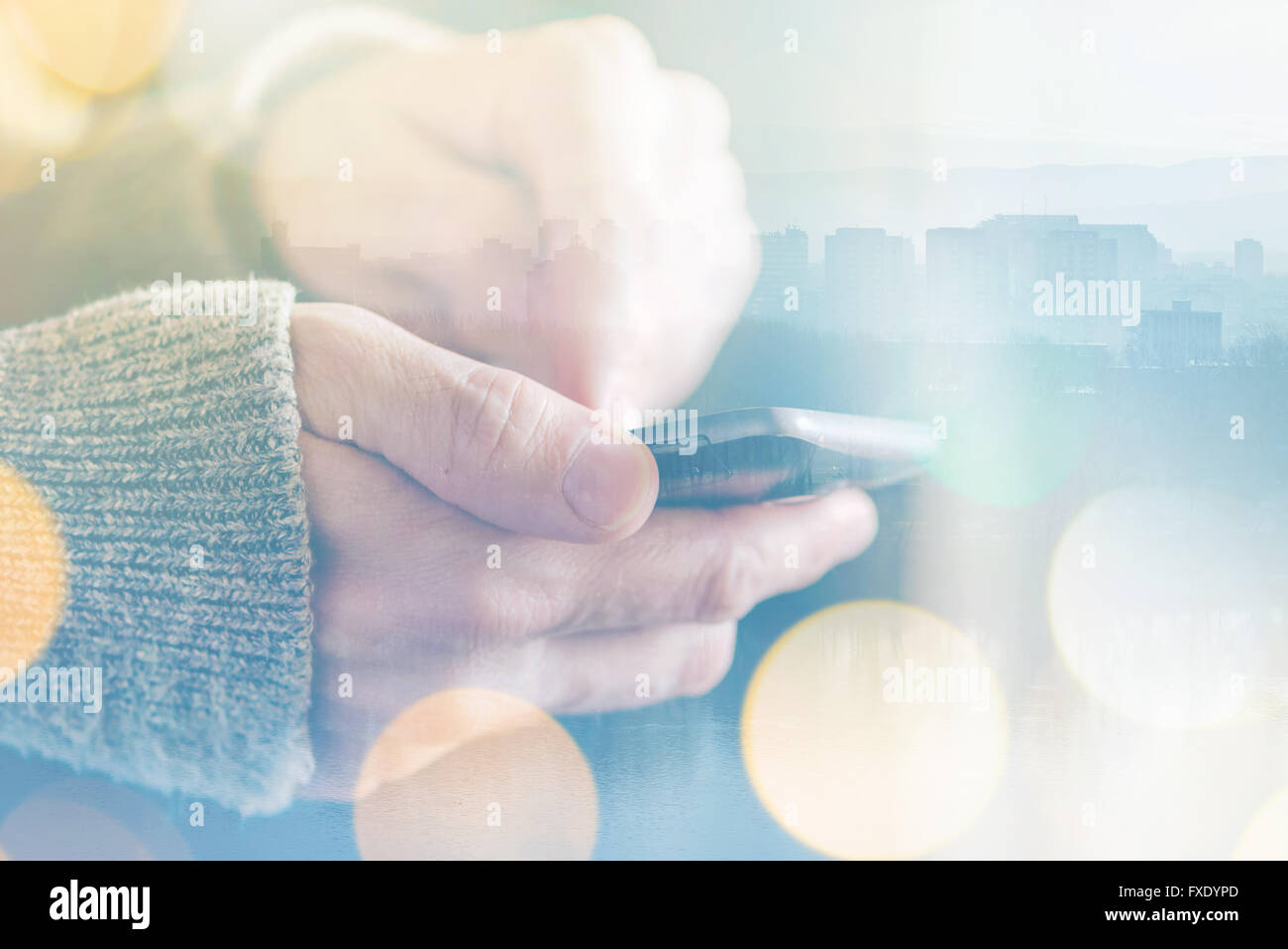 Man sending text message on smartphone, morning sunlight through the ...