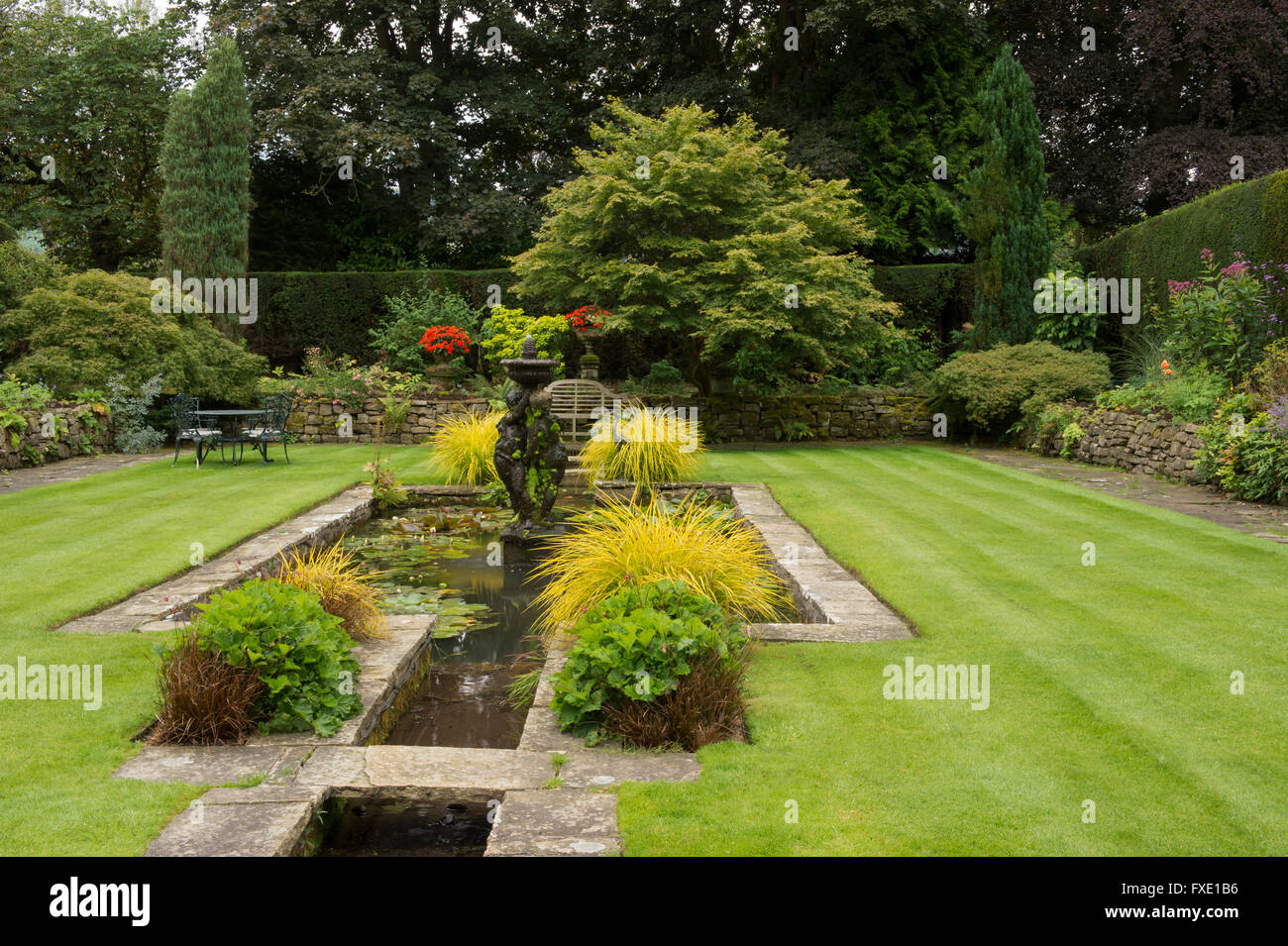 A beautiful, private, traditional, landscaped, country garden, West Yorkshire, England  - ornamental pond, fountain, seating area and striped lawn. Stock Photo