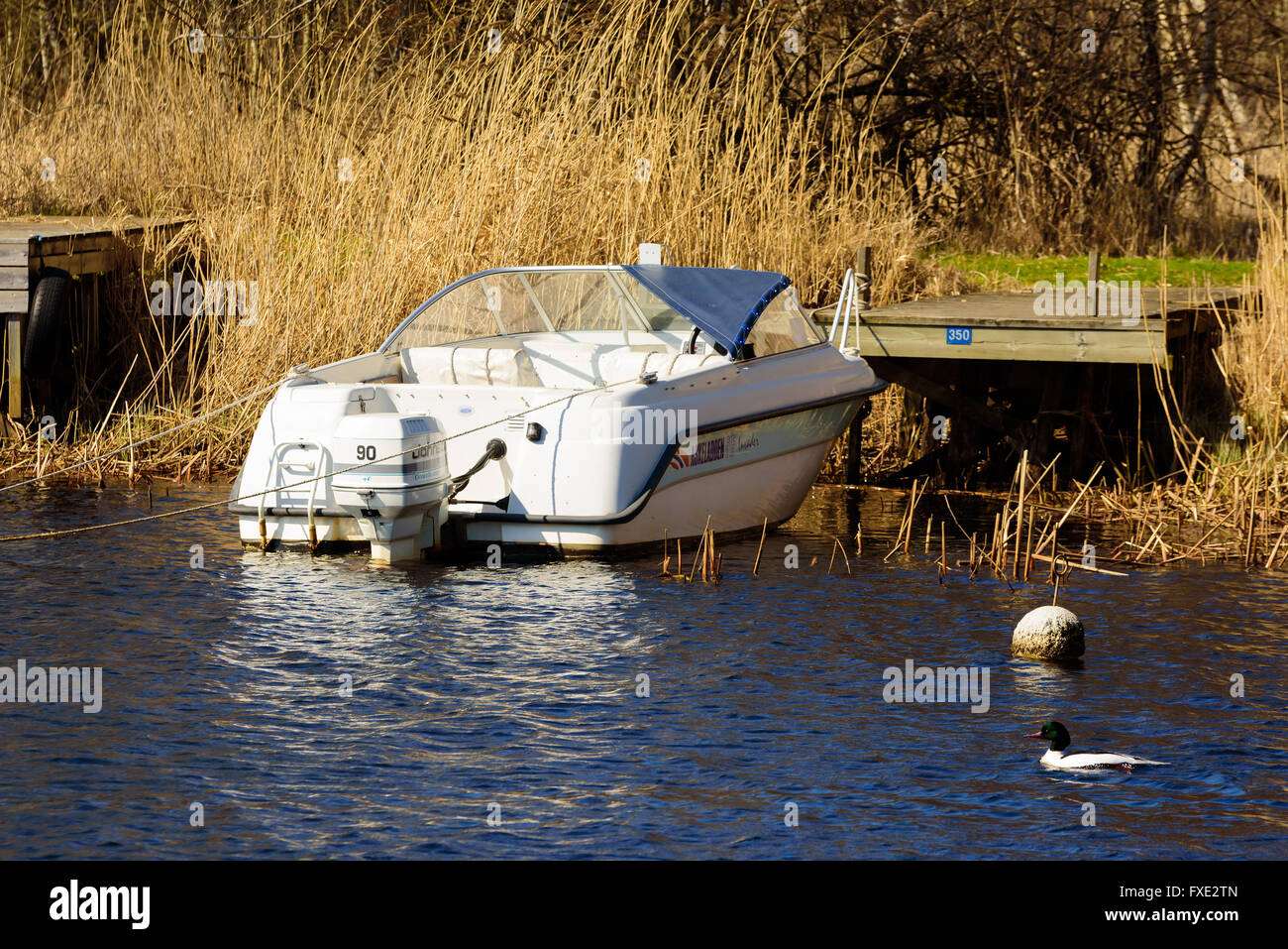 Lyckeby, Sweden - April 7, 2016: White Askeladden 515 open motorboat with Johnson 90 motor, moored at a wooden jetty seen from t Stock Photo