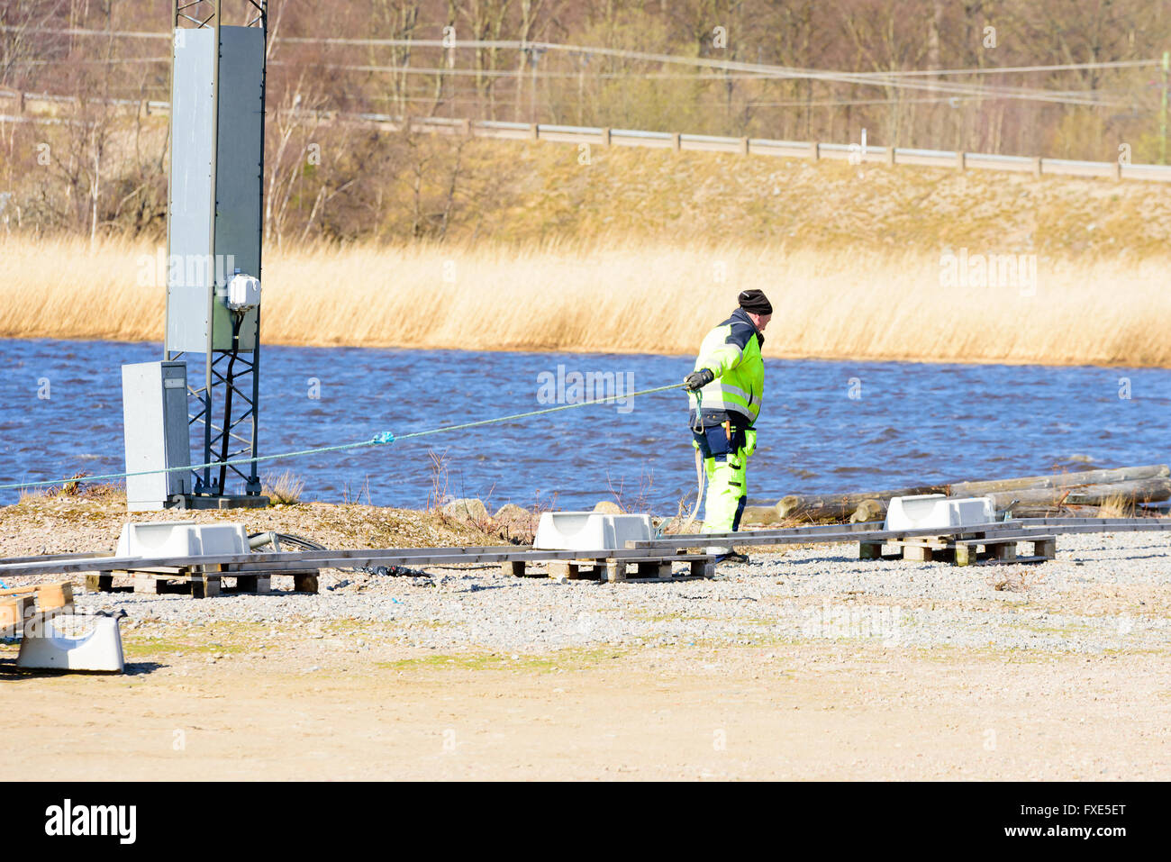 Karlskrona, Sweden - April 7, 2016: Assembly of underwater sewage pipeline in public area. Here a man is pulling out some line t Stock Photo