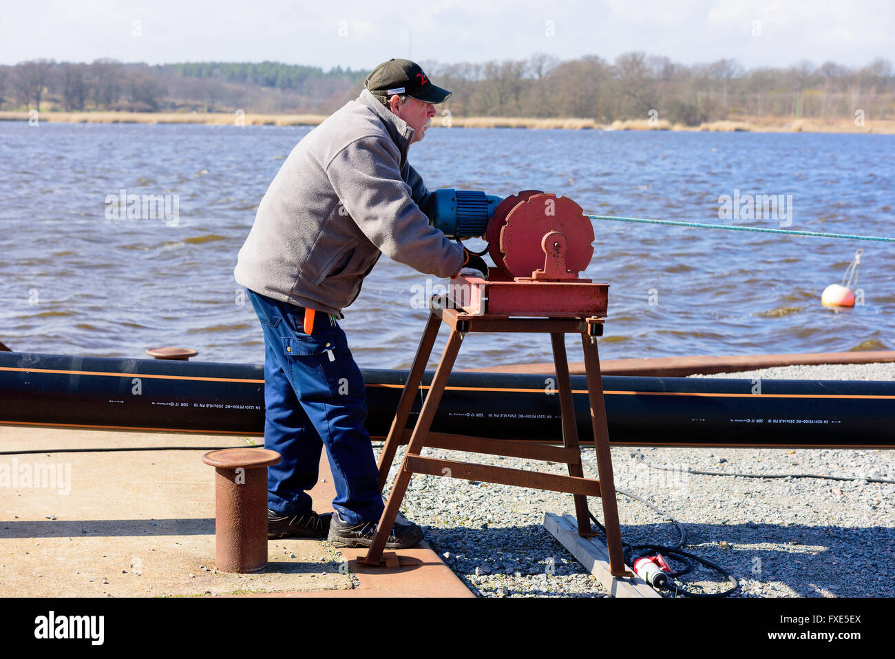 Karlskrona, Sweden - April 7, 2016: Assembly of underwater sewage pipeline in public area. Here a man is using a motorized winch Stock Photo