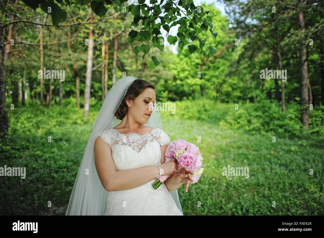 Portrait of cute bride with peony wedding bouquet at hands at wood ...