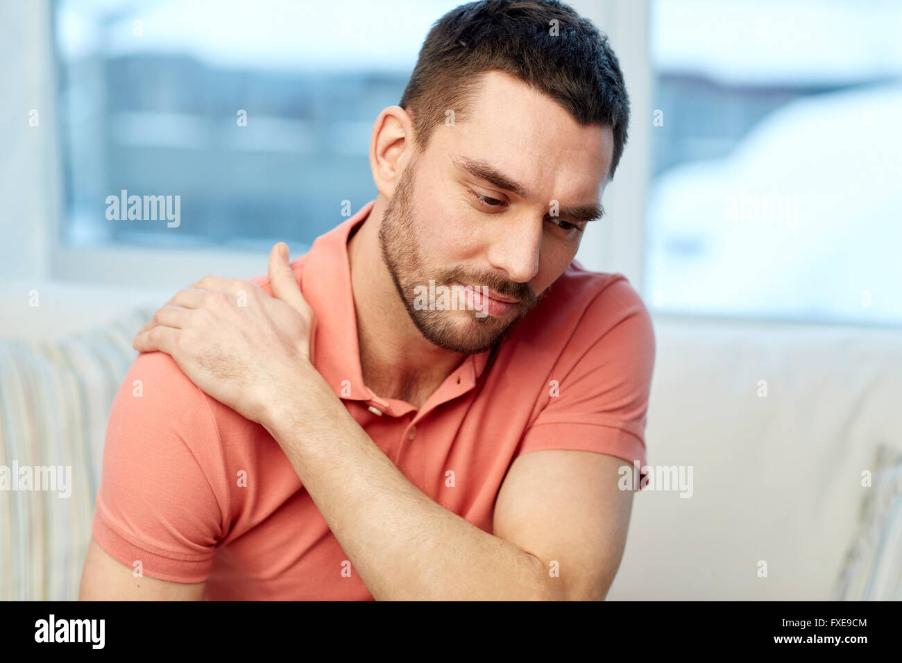unhappy man suffering from neck pain at home Stock Photo - Alamy
