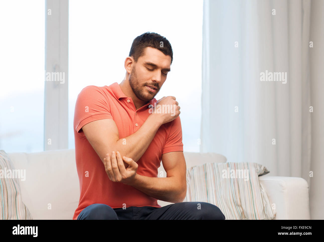 unhappy man suffering from pain in hand at home Stock Photo - Alamy